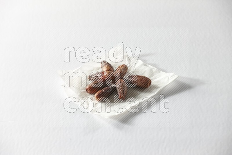 Dried dates on a crumpled piece of paper on a white background in different angles