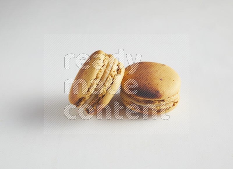 45º Shot of two Yellow Crème Brulée macarons on white background