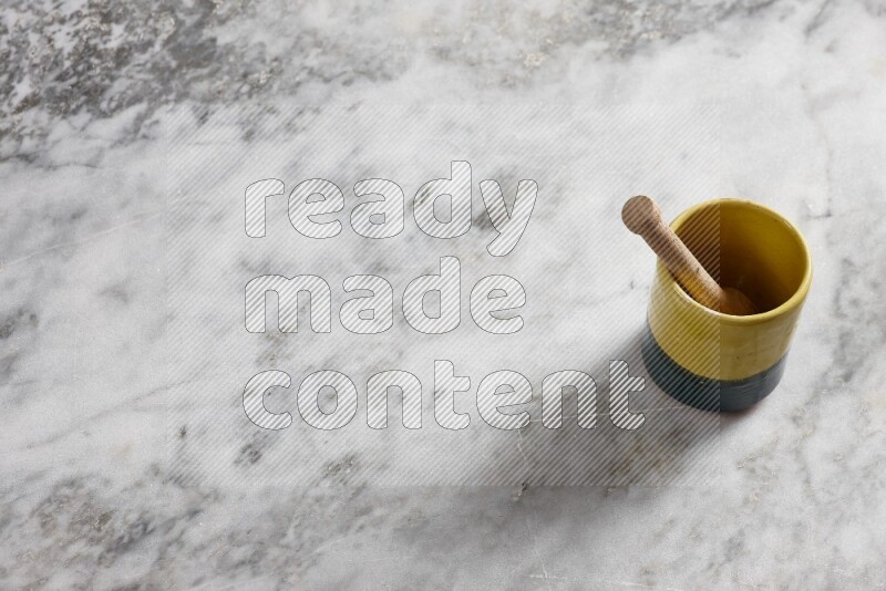 Multicolored pottery cup with wooden honey dipper in it on grey marble background