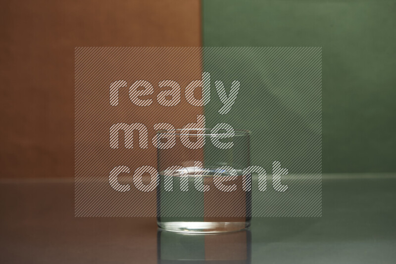 تظهر الصورة أواني زجاجية ممتلئة بالماء موضوعة على خلفية من اللونين البني والأخضر الغامق