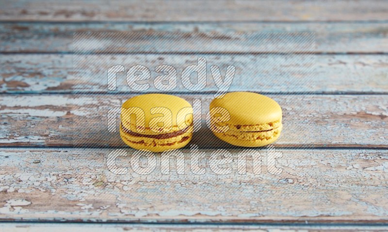 45º Shot of two Yellow Lemon macarons on light blue wooden background