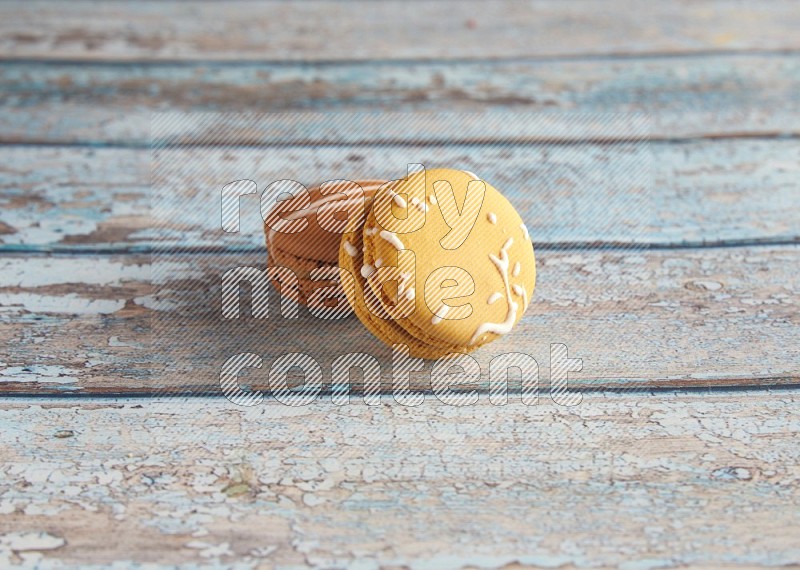 45º Shot of of two assorted Brown Irish Cream, and Yellow Piña Colada macarons on light blue background