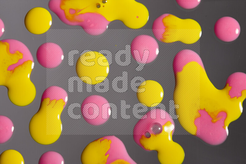 Close-ups of abstract pink and yellow paint droplets on the surface