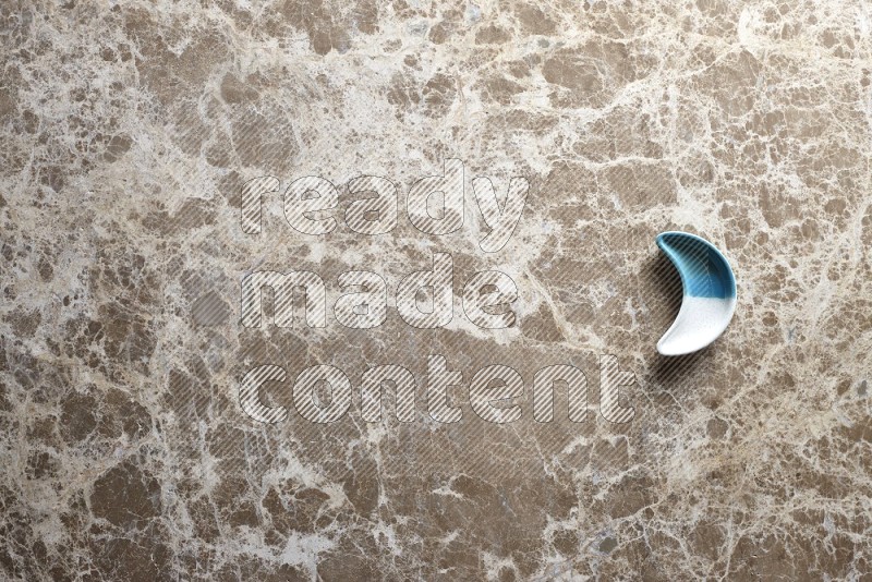 A pottery crescent plate on beige marble background