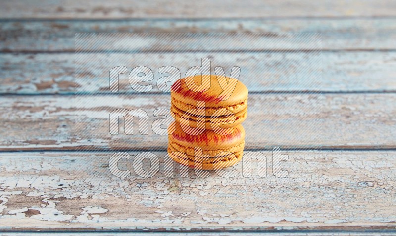45º Shot of two orange Exotic macarons on light blue wooden background