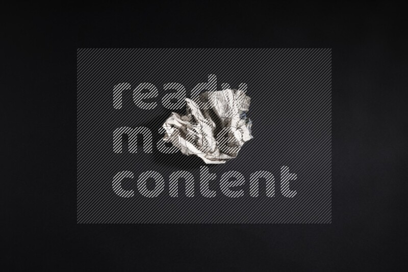 Crumpled newspaper sheet on black background