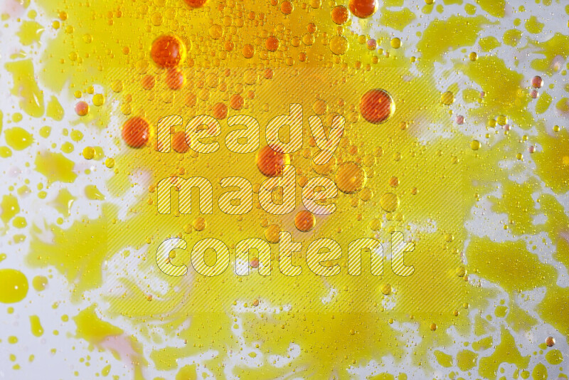 Close-ups of abstract yellow and red watercolor drops on oil Surface on white background