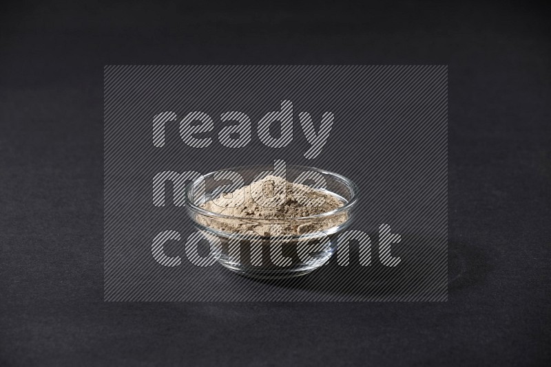 A glass bowl full of garlic powder on a black flooring in different angles