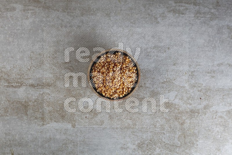 corn kernel in a wooden bowl on a grey textured countertop