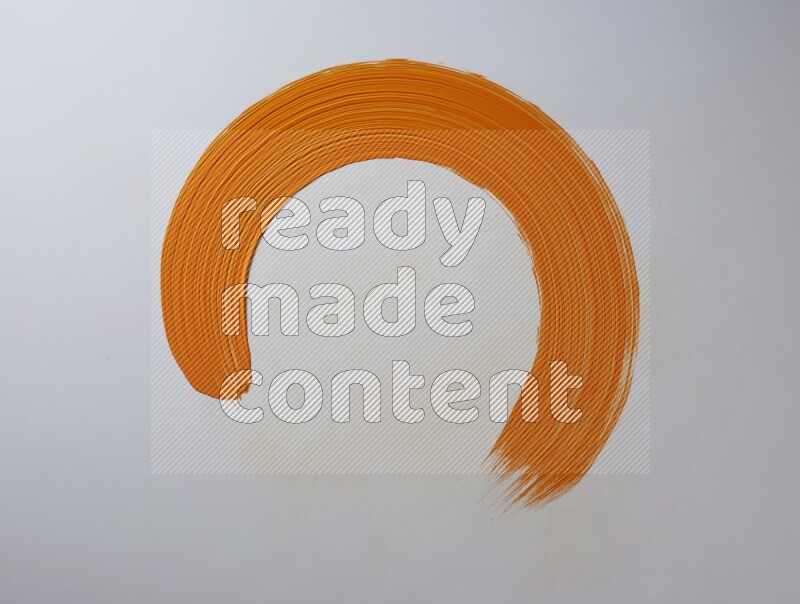 An orange circular painting brush stroke on white background