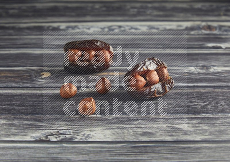two hazelnut stuffed madjoul dates on a wooden grey background