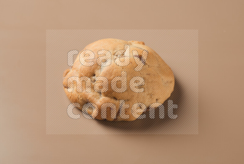 a whole chocolate chip cookie on a brown background