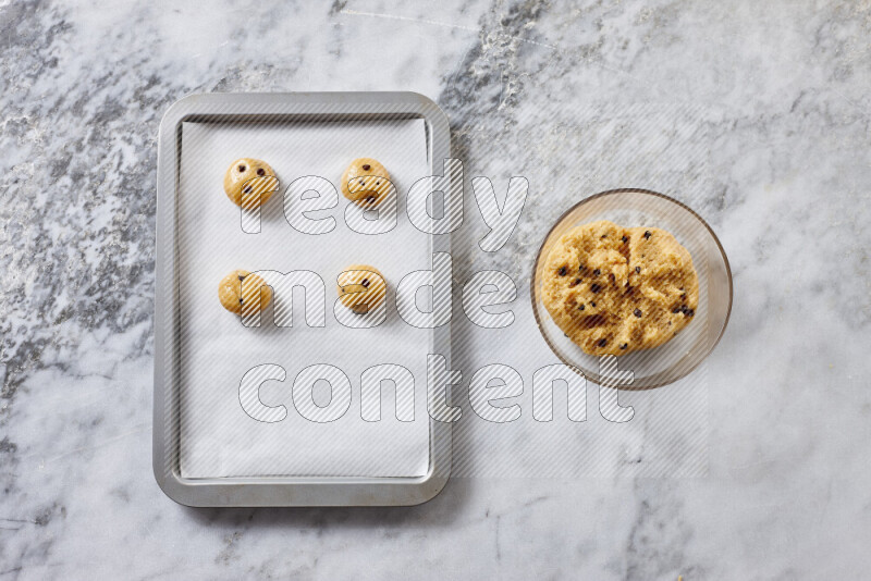 Cookies step by step with its ingredient, flour, butter, brown sugar, egg, vanilla extract, white sugar, chocolate chips and baking soda on grey marble background