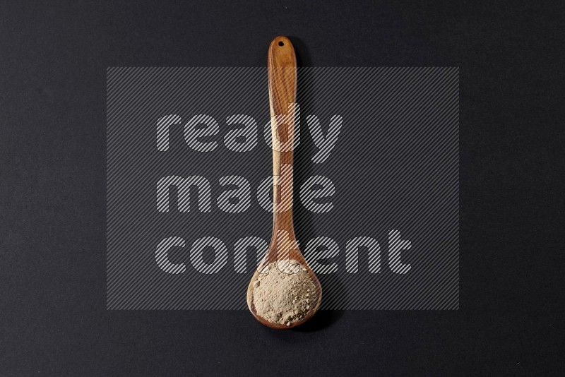 A wooden ladle full of garlic powder on a black flooring in different angles