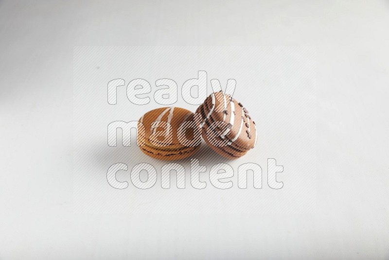45º Shot of of two assorted Brown Irish Cream, and Brown white Chocolate Caramel macarons on white background
