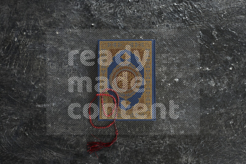 Quran with a prayer beads on textured black background