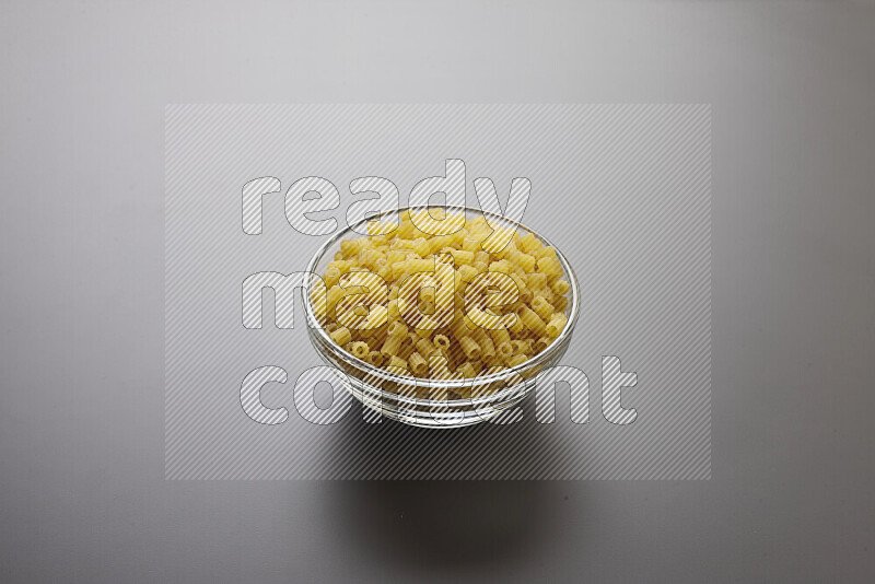Small rings pasta in a glass bowl on grey background