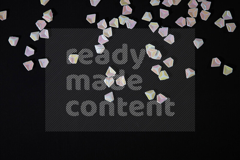 Colorful plastic shards for decoration scattered on a black background