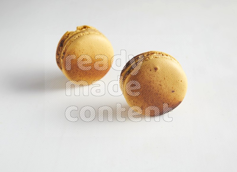 45º Shot of two Yellow Crème Brulée macarons on white background