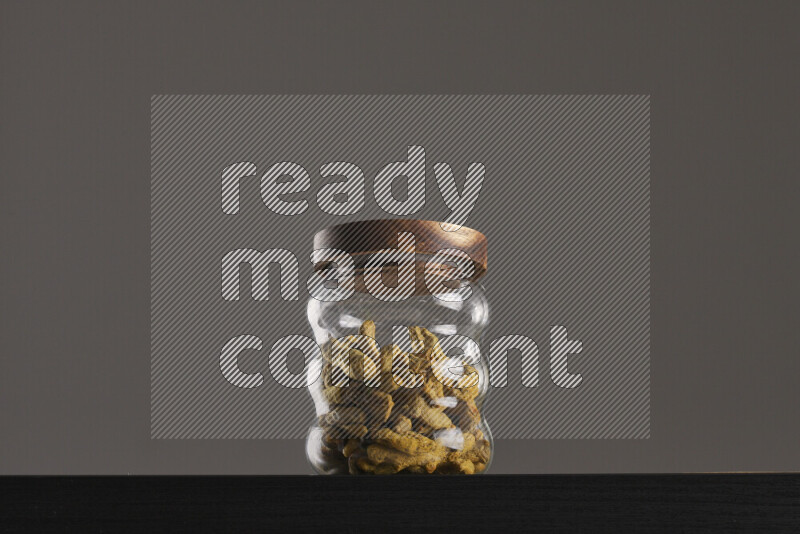 Turmeric in a glass jar on black background