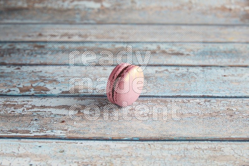 45º Shot of Purple Strawberry macaron on light blue wooden background