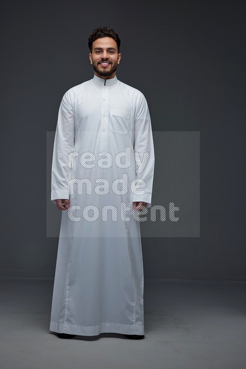 A Saudi man wearing Thobe standing and making different poses eye level on a gray background
