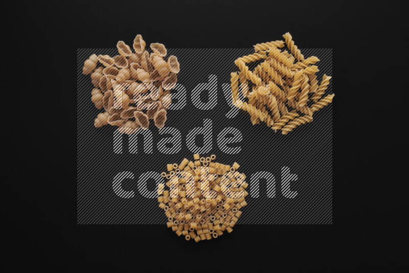 Different pasta types in bunches on black background