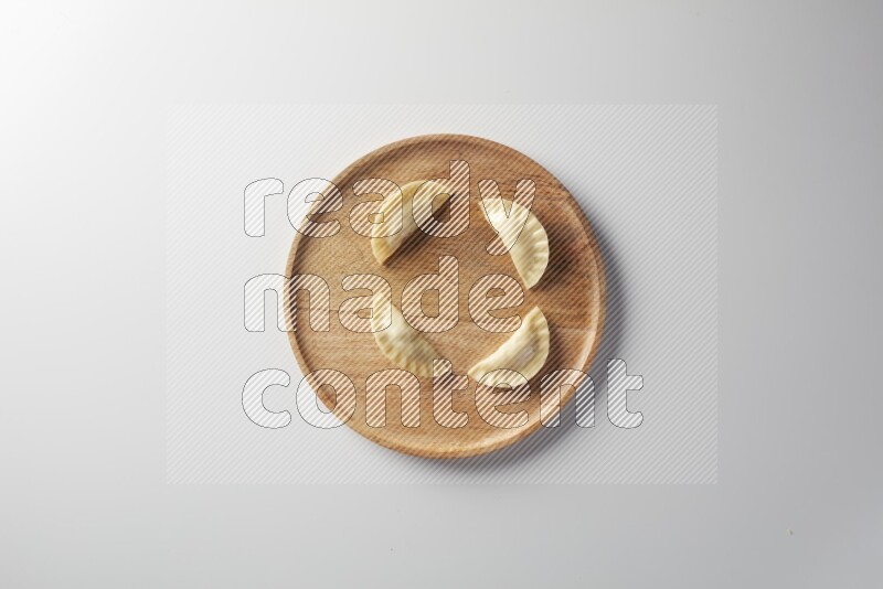 Four Sambosas on a wooden round plate on a white background