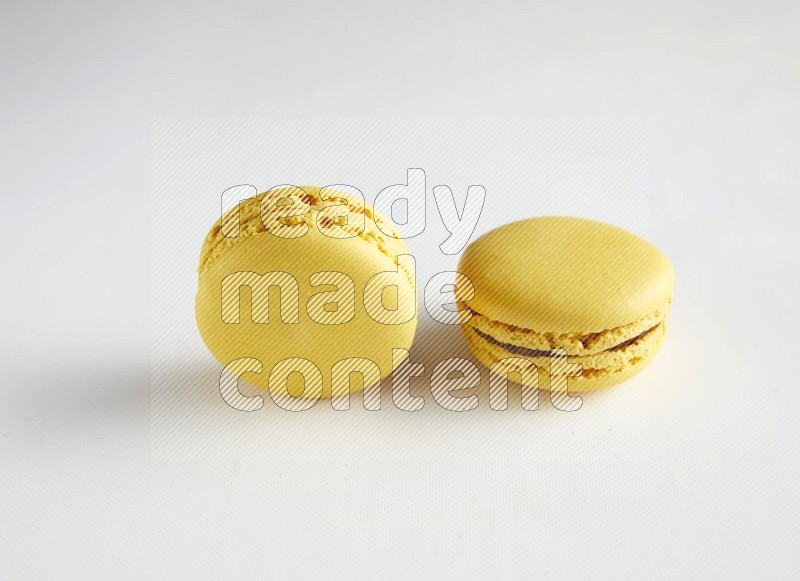 45º Shot of two Yellow Lemon macarons on white background