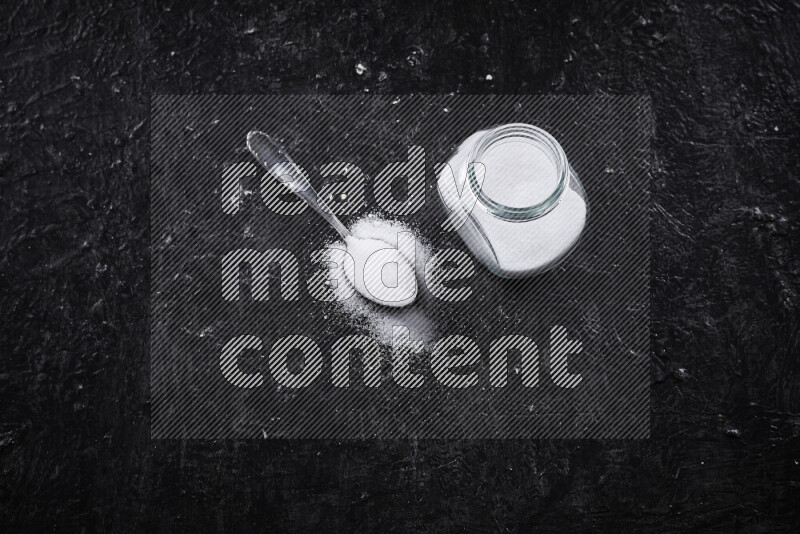 A glass jar full of fine table salt on black background