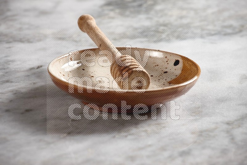 Multicolored Pottery Plate with wooden honey handle in it, on grey marble flooring, 15 degree angle