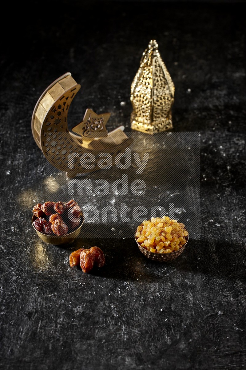 Dates in a metal bowl with raisins beside golden lanterns in a dark setup