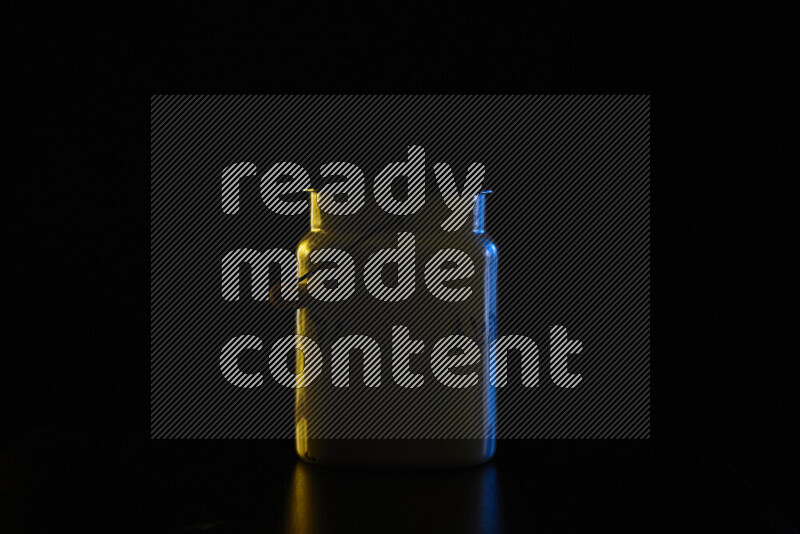 A vintage milk canister with colored rim light against black background