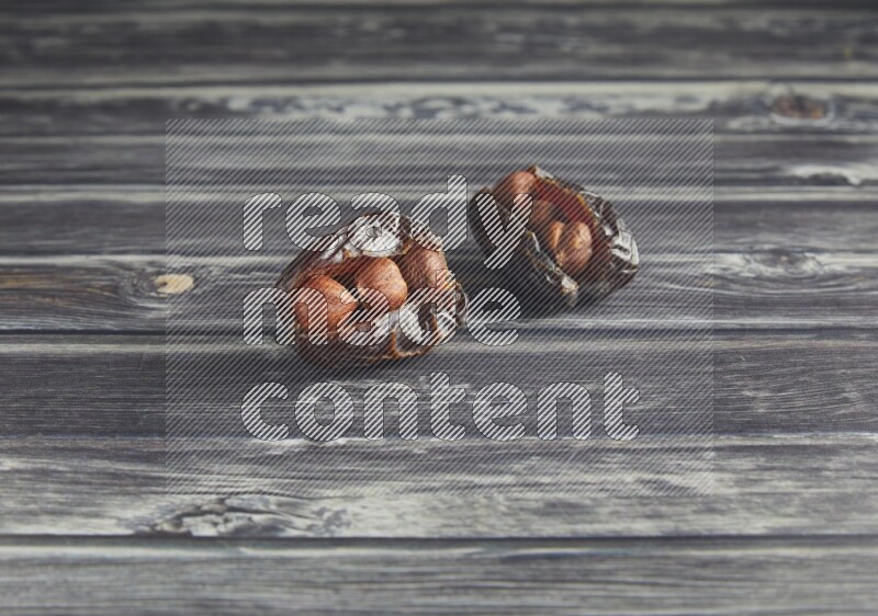 two hazelnut stuffed madjoul dates on a wooden grey background