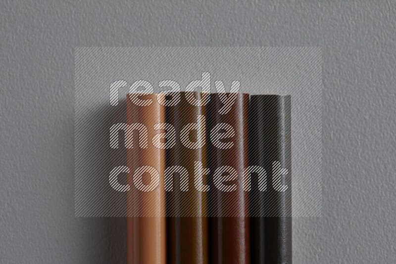 A collection of colored pencils arranged showcasing a gradient of brown hues on grey background