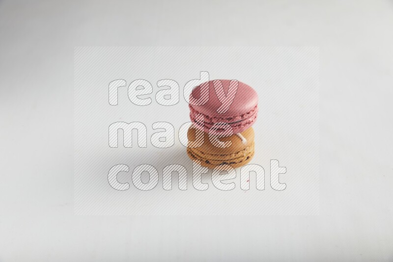 45º Shot of of two assorted Brown Irish Cream, and Pink Raspberry macarons on white background