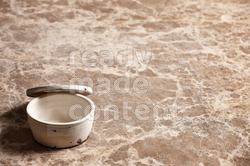 A white pottery bowl on beige marble background