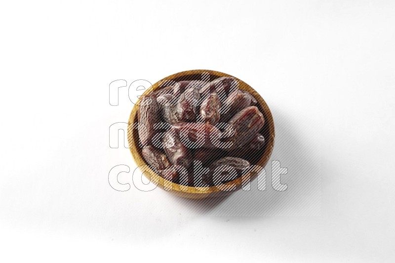 Dates in a wooden bowl on white background