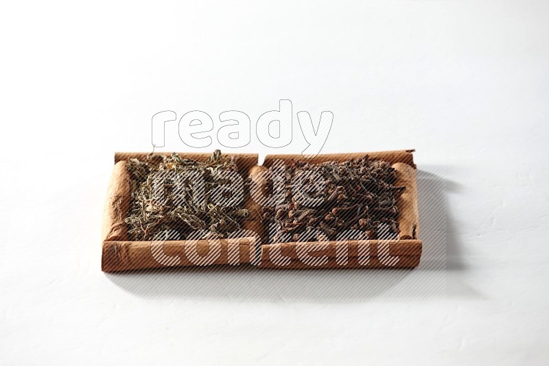 2 squares of cinnamon sticks full of cloves and dried basil on white flooring