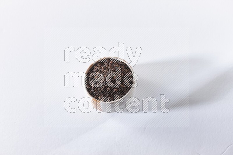 وعاء بيج من السيراميك ممتلئ بحبوب القرنفل علي خلفية بيضاء