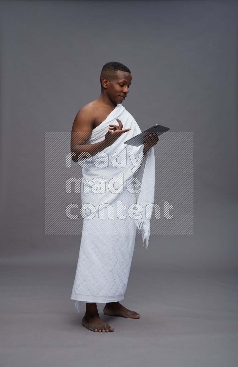 A man wearing Ehram Standing working on tablet on gray background