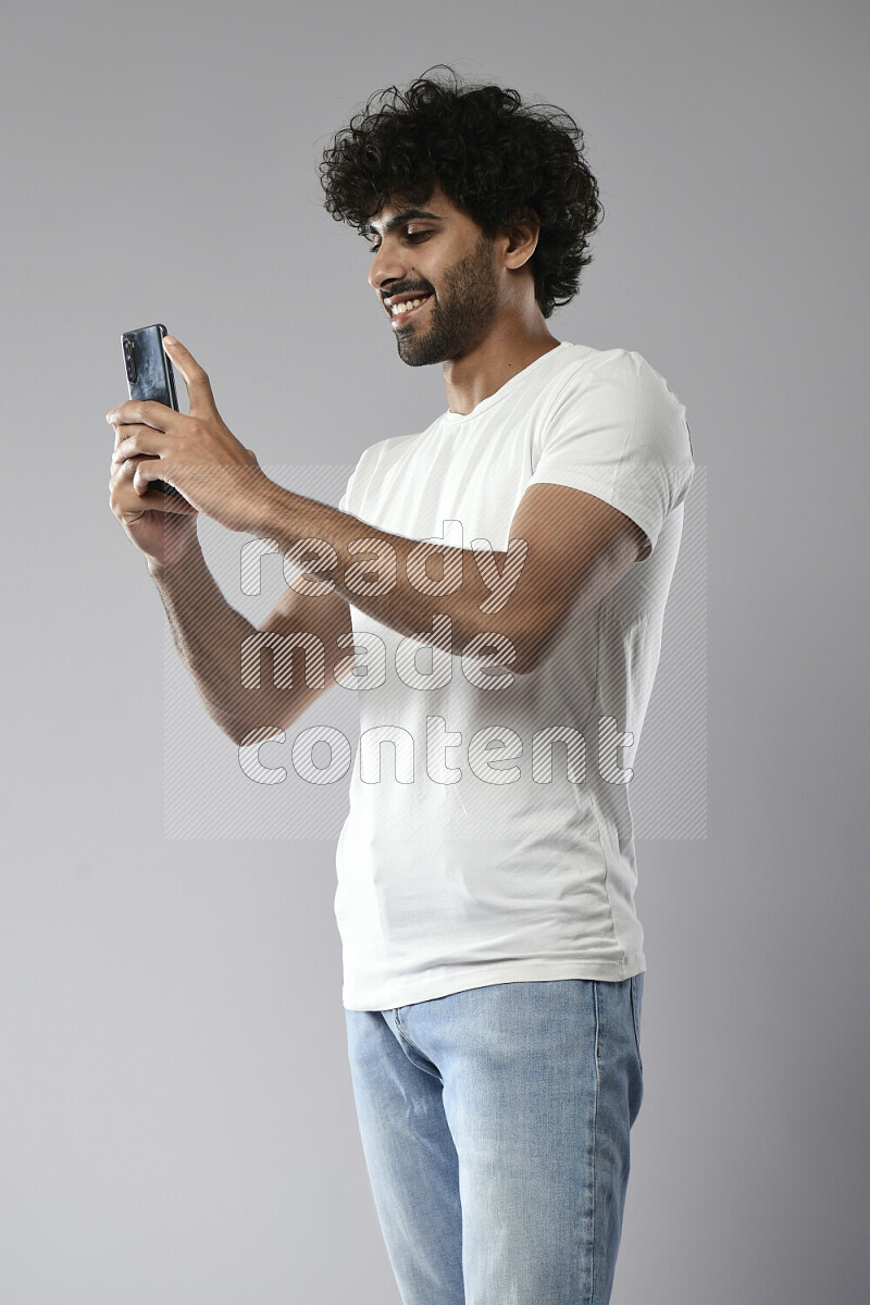 A man wearing casual standing and shooting with his phone on white background