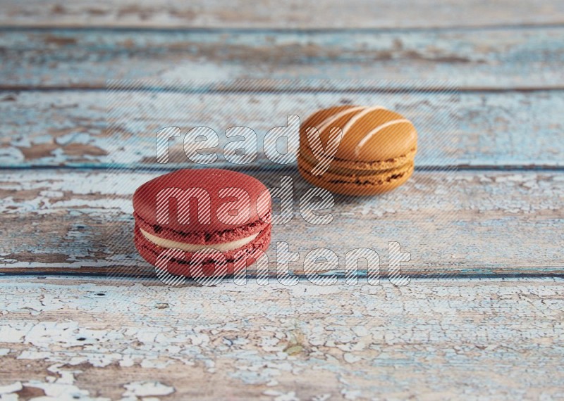 45º Shot of of two assorted Brown Irish Cream, and Red Velvet macarons on light blue background