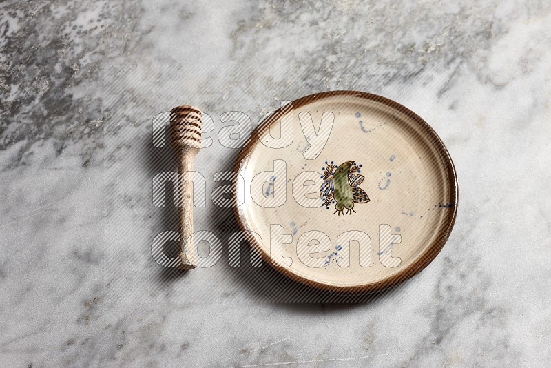 Decorative Pottery Plate with wooden honey handle on the side with grey marble flooring, 65 degree angle