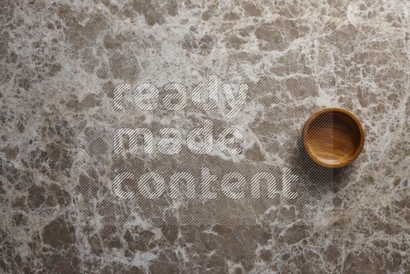 A wooden bowl on beige marble background