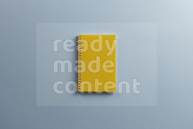 A yellow notebook with different school supplies on blue background