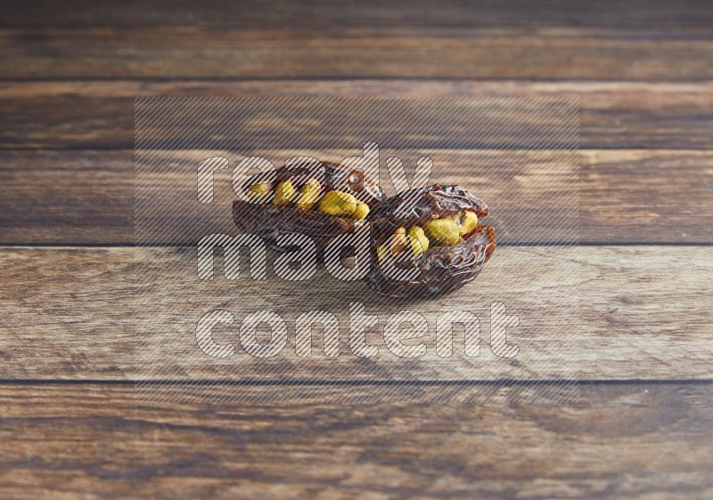 two pistachio stuffed madjoul date on a wooden background