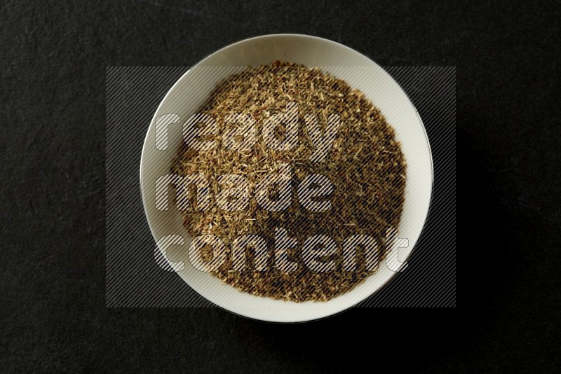 white ceramic round sauce dish filled with herbs on grey textured countertop