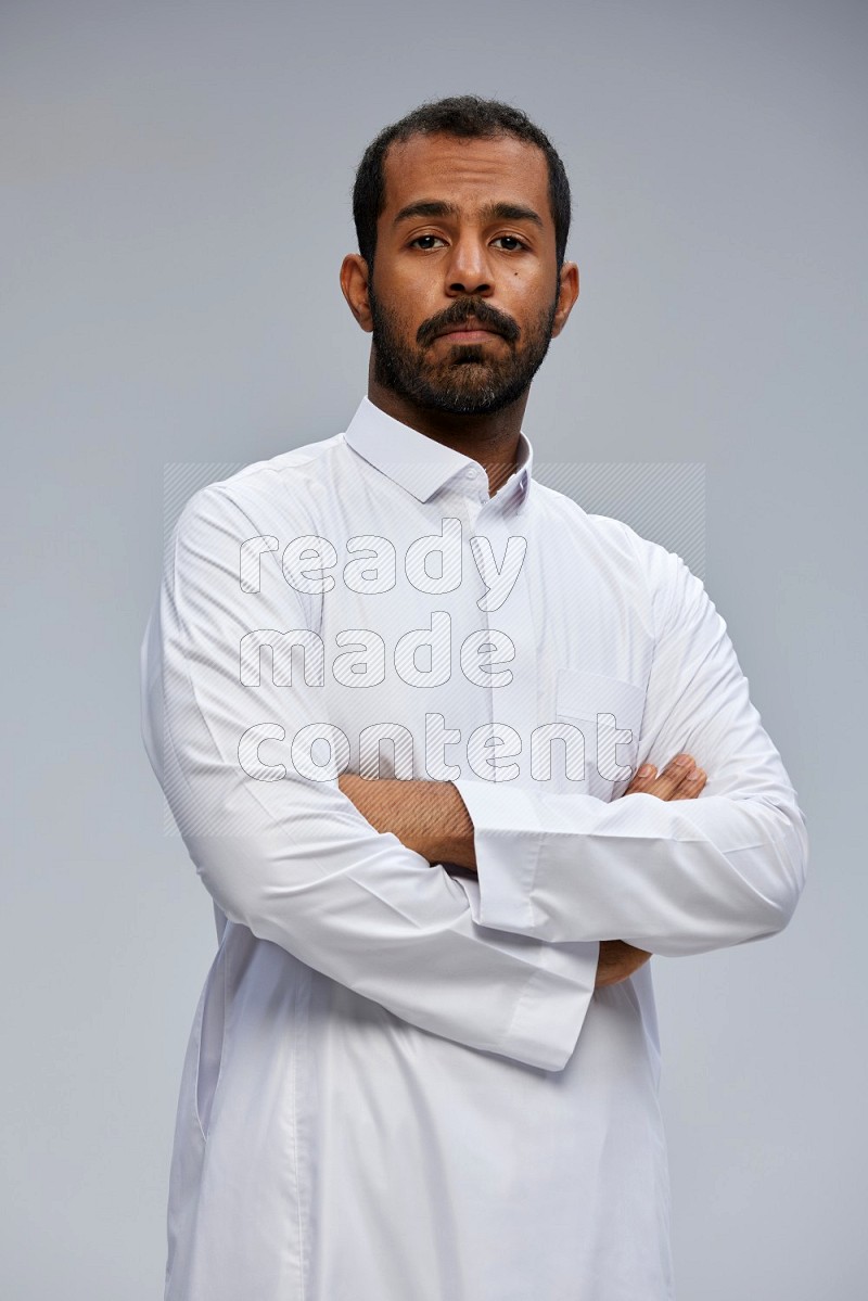 Saudi man wearing Thob standing with crossed arms on Gray background