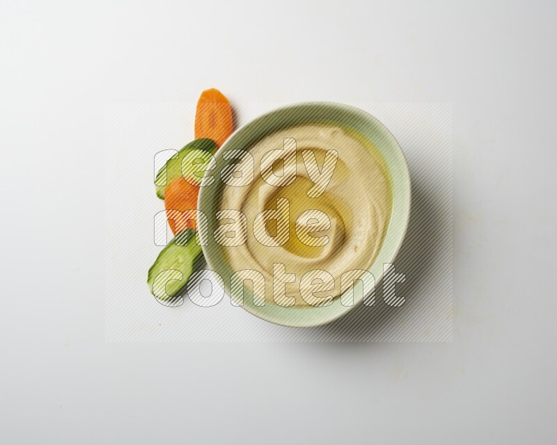 Hummus in a green plate garnished with olive oil on a white background
